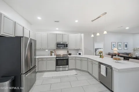 a kitchen with stainless steel appliances granite countertop a sink stove refrigerator and cabinets