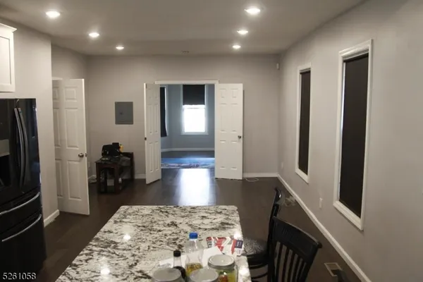a living room with stainless steel appliances furniture a rug and a refrigerator