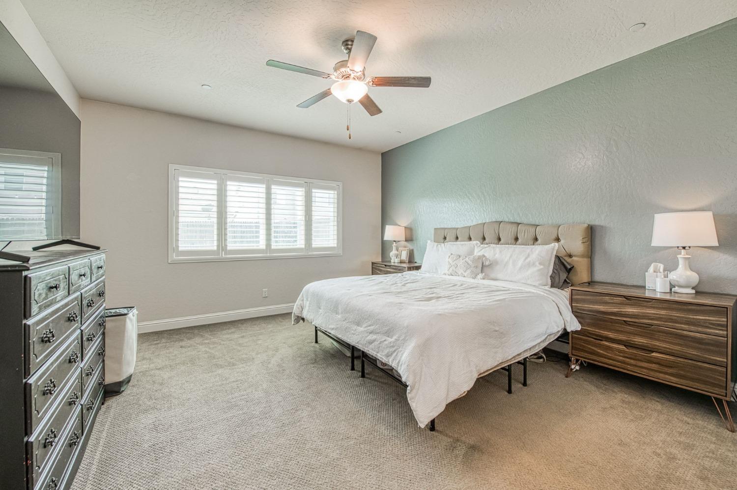 574 Expedition Way Madera, CA 93636 - Photo 18 of 26 a bedroom with a bed next to a window and a chandelier