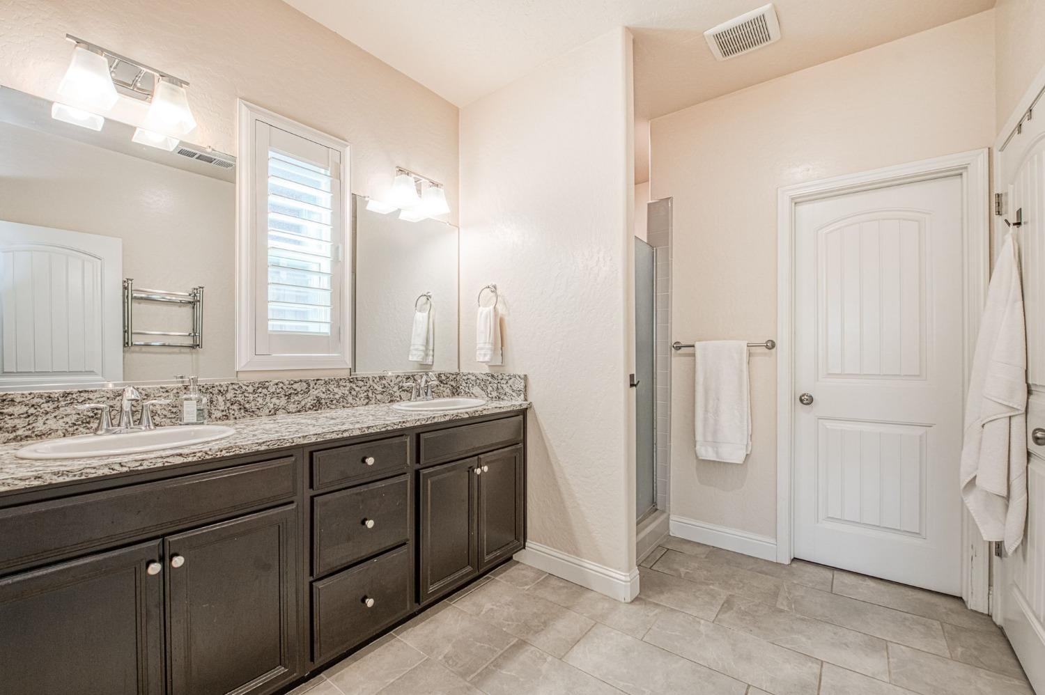 574 Expedition Way Madera, CA 93636 - Photo 20 of 26 a bathroom with a granite countertop sink a mirror and a shower