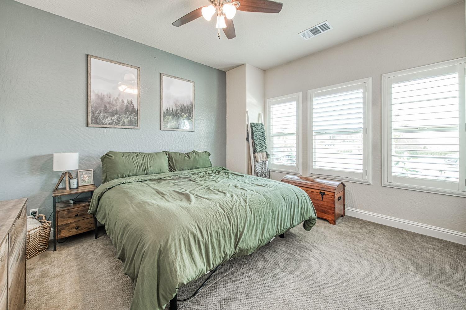 574 Expedition Way Madera, CA 93636 - Photo 4 of 26 a spacious bedroom with a bed and a chandelier