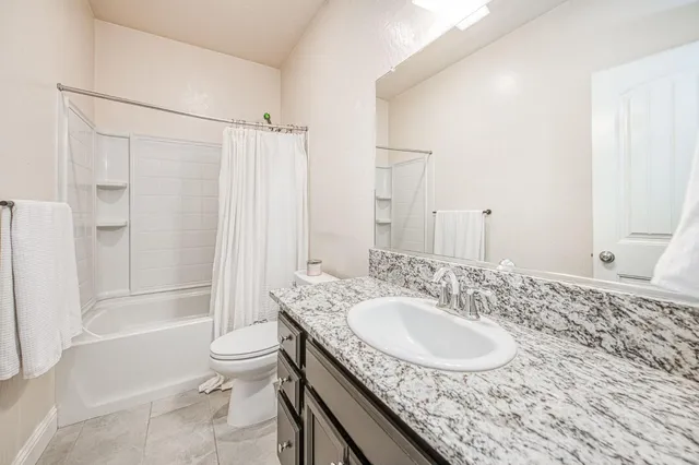 a bathroom with a granite countertop sink toilet and shower