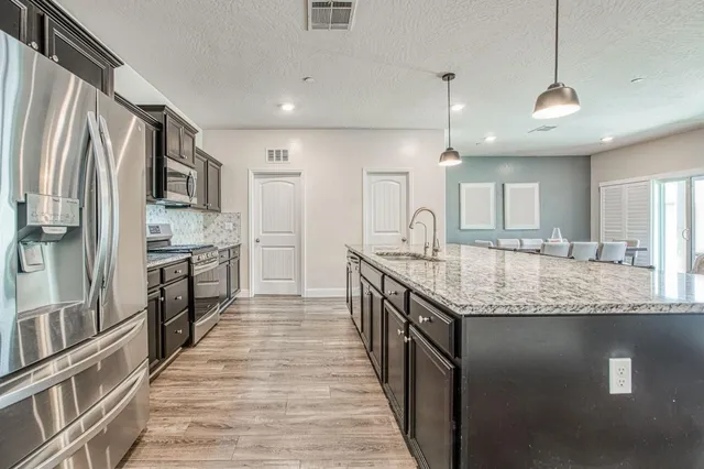 a large kitchen with a center island wooden floor stainless steel appliances and a window