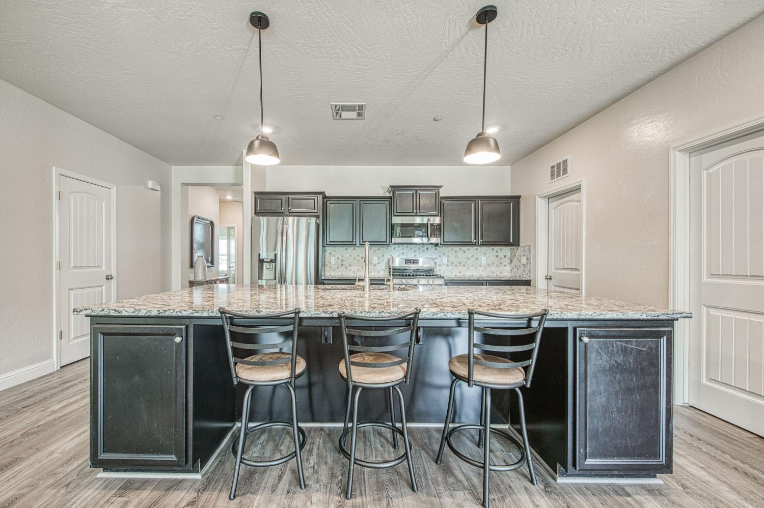 574 Expedition Way Madera, CA 93636 - Photo 10 of 26 a kitchen with kitchen island granite countertop a sink a center island and cabinets