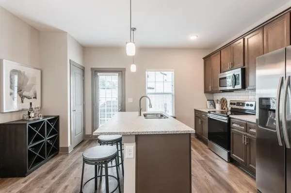 a kitchen with stainless steel appliances granite countertop a stove top oven a sink dishwasher a dining table and chairs with wooden floor