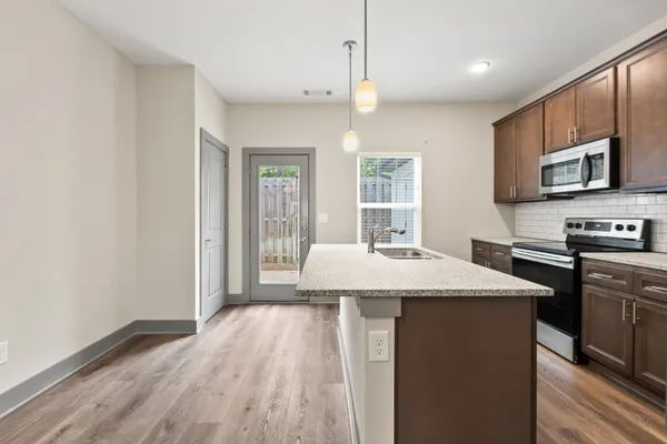 a kitchen with stainless steel appliances granite countertop a sink a microwave a refrigerator and a stove