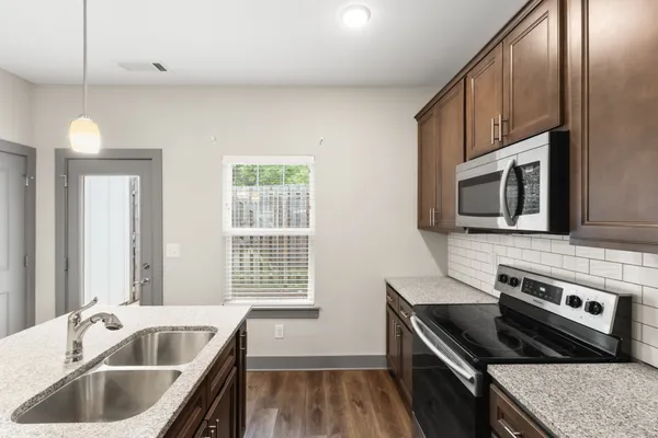 a kitchen with stainless steel appliances granite countertop a sink a microwave a refrigerator and cabinets