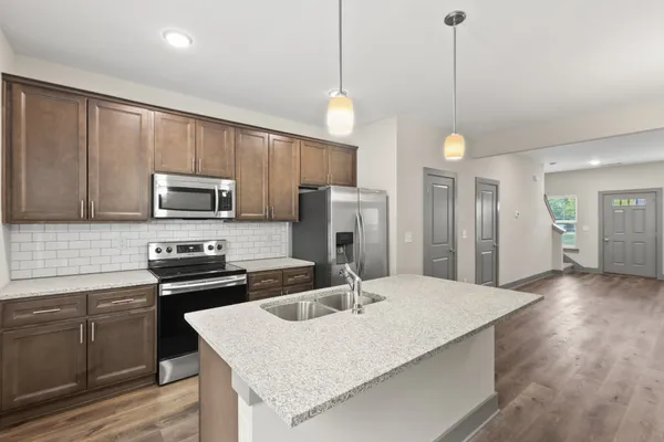 a kitchen with kitchen island granite countertop a sink appliances and cabinets