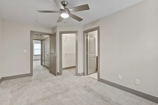 an empty room with closet and a ceiling fan