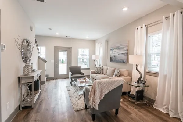 a living room with furniture a wooden floor and a large window