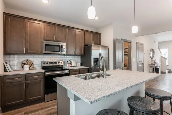 a kitchen with stainless steel appliances granite countertop a sink stove refrigerator and cabinets