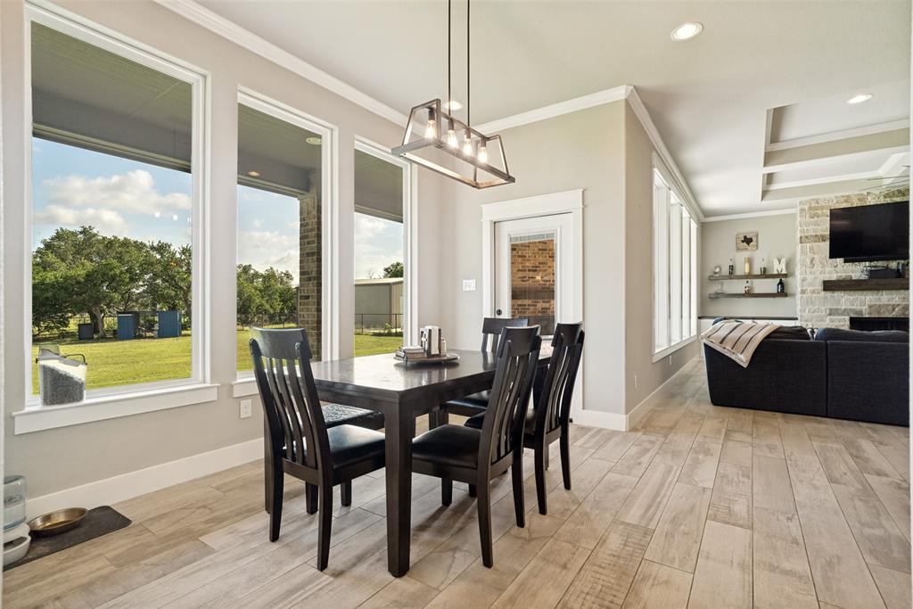 6913 Veal Station Road Weatherford, TX 76085 - Photo 12 of 31 Dining area with wood-finish flooring, a linear chandelier, and multiple tall windows providing abundant natural light