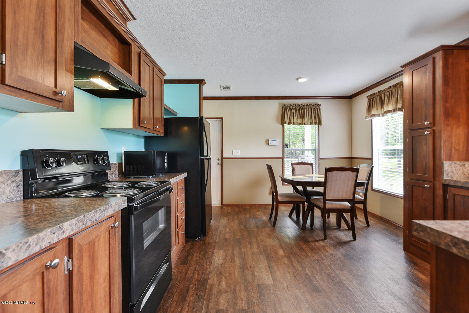54464 Sherwood Road Callahan, FL 32011 - Photo 8 of 25 a kitchen with stainless steel appliances granite countertop a stove a refrigerator a sink a dining table and chairs with wooden floor