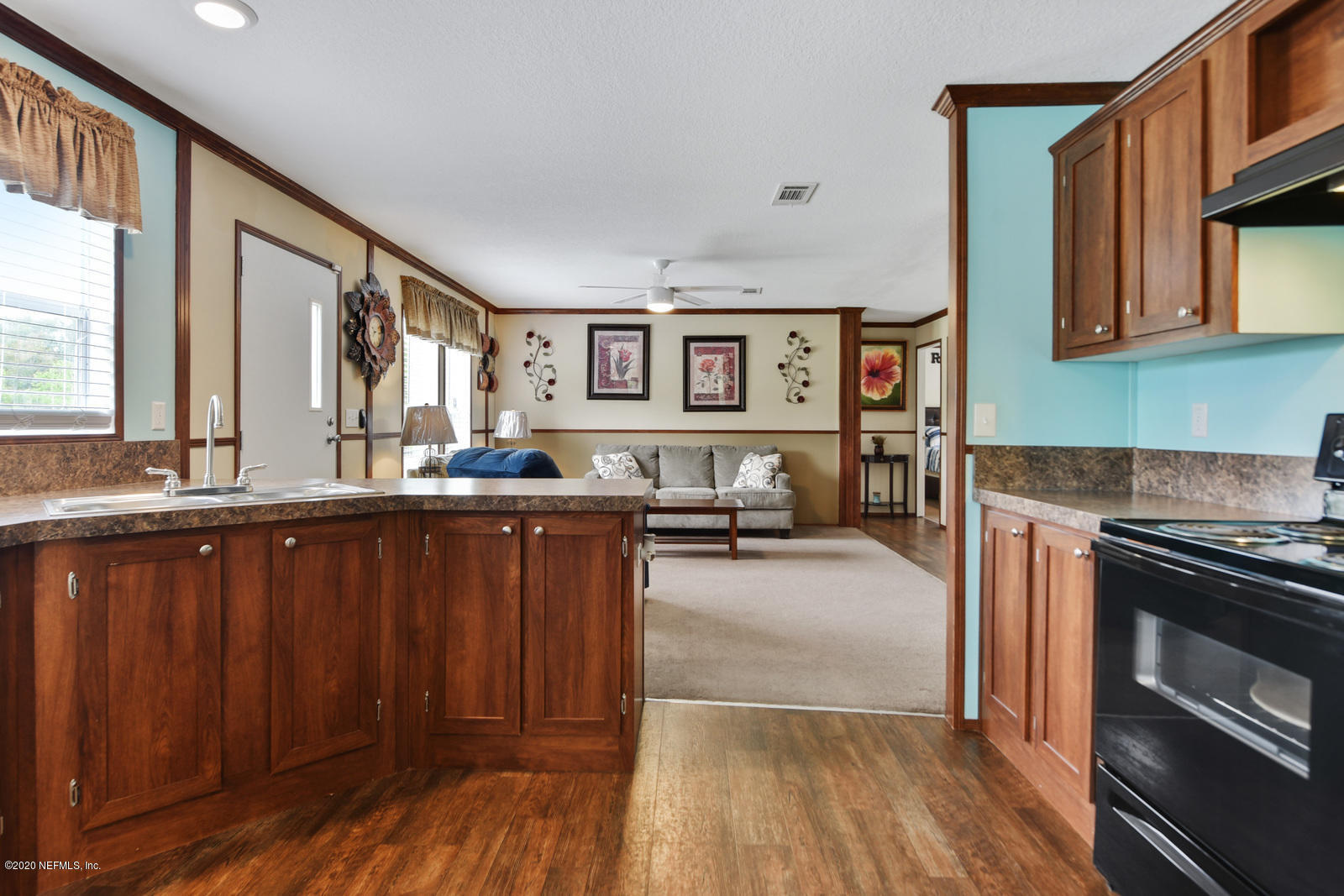 54464 Sherwood Road Callahan, FL 32011 - Photo 10 of 25 a kitchen with granite countertop a stove a sink dishwasher and cabinets with wooden floor