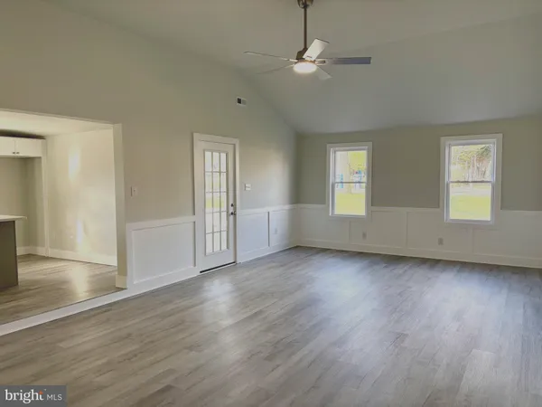 an empty room with wooden floor cabinet and windows