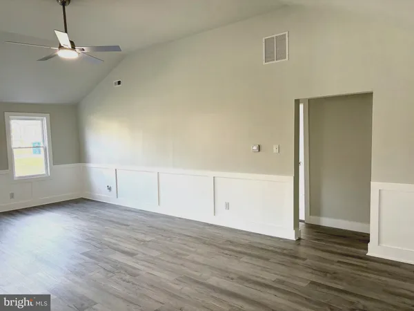 an empty room with wooden floor cabinet and windows