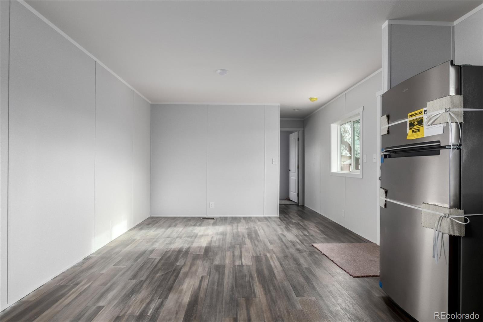 105 Longs Street Brighton, CO 80601 - Photo 10 of 27 a view of empty room with wooden floor and window