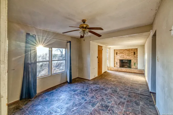 a view of n empty room with window and a kitchen