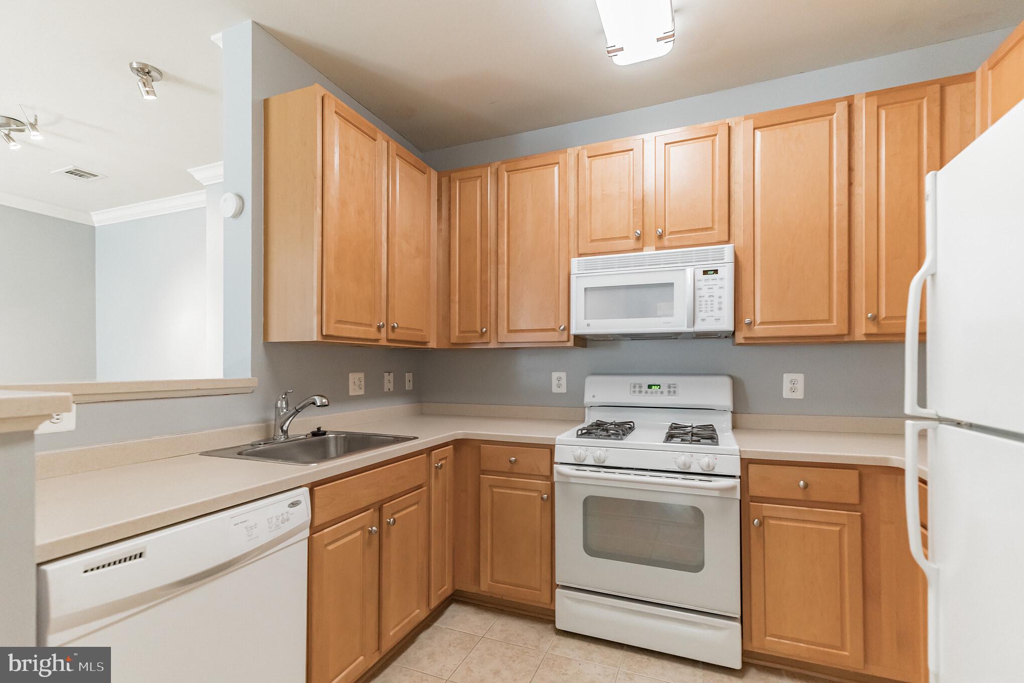 12001 Market Street, Unit 106 Reston, VA 20190 - Photo 11 of 26 a kitchen with granite countertop white cabinets and white appliances