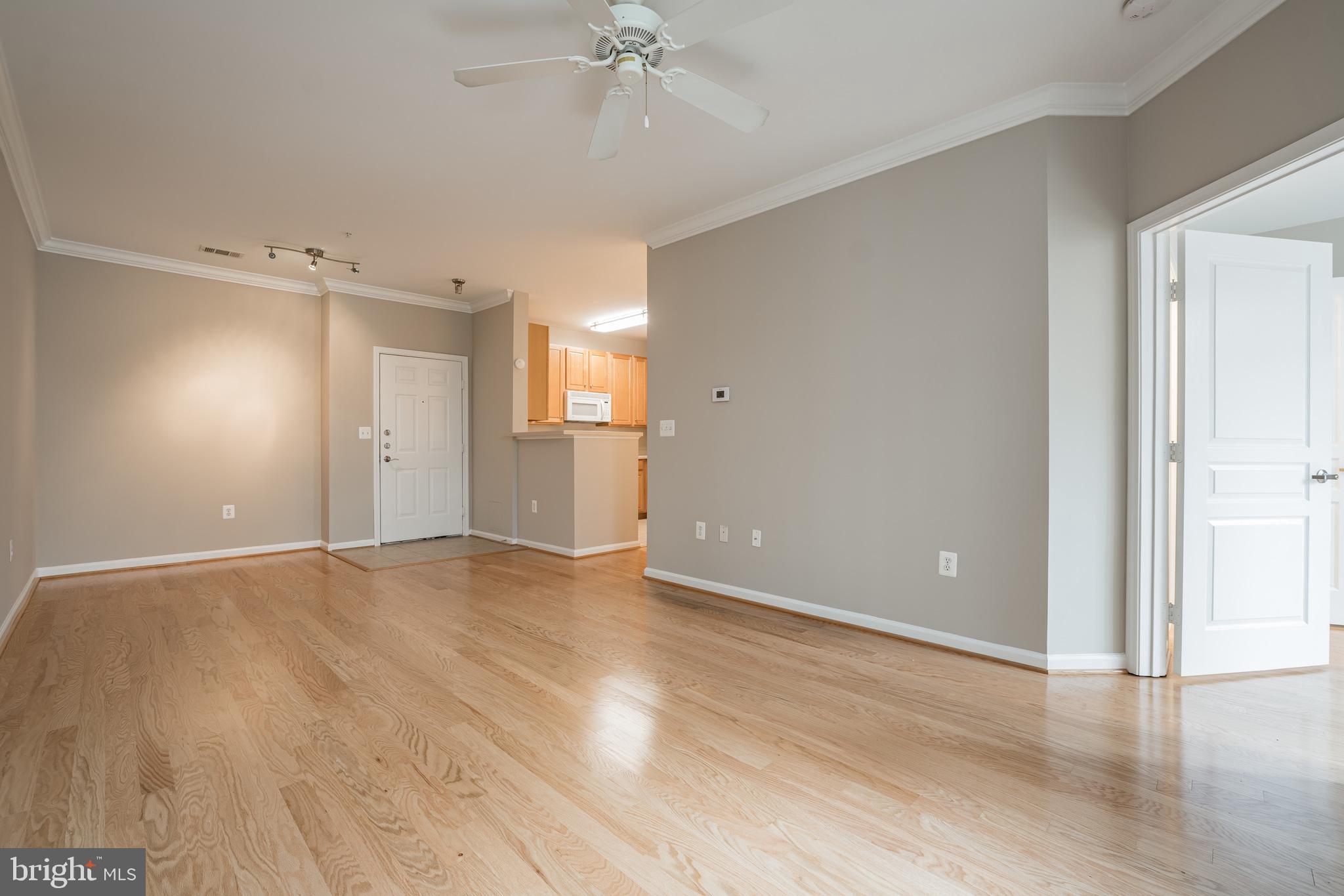 12001 Market Street, Unit 106 Reston, VA 20190 - Photo 6 of 26 an empty room with wooden floor and chandelier fan