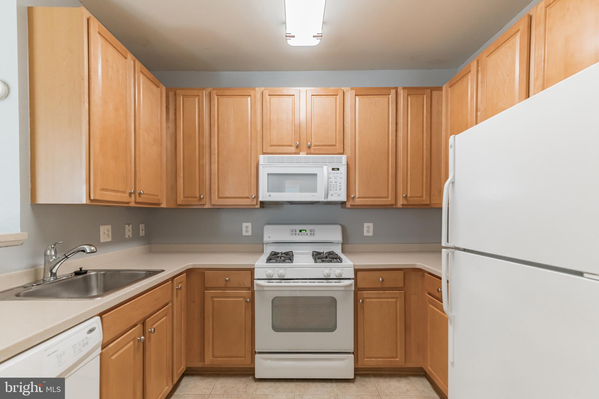 12001 Market Street, Unit 106 Reston, VA 20190 - Photo 8 of 26 a kitchen with a sink a stove and cabinets