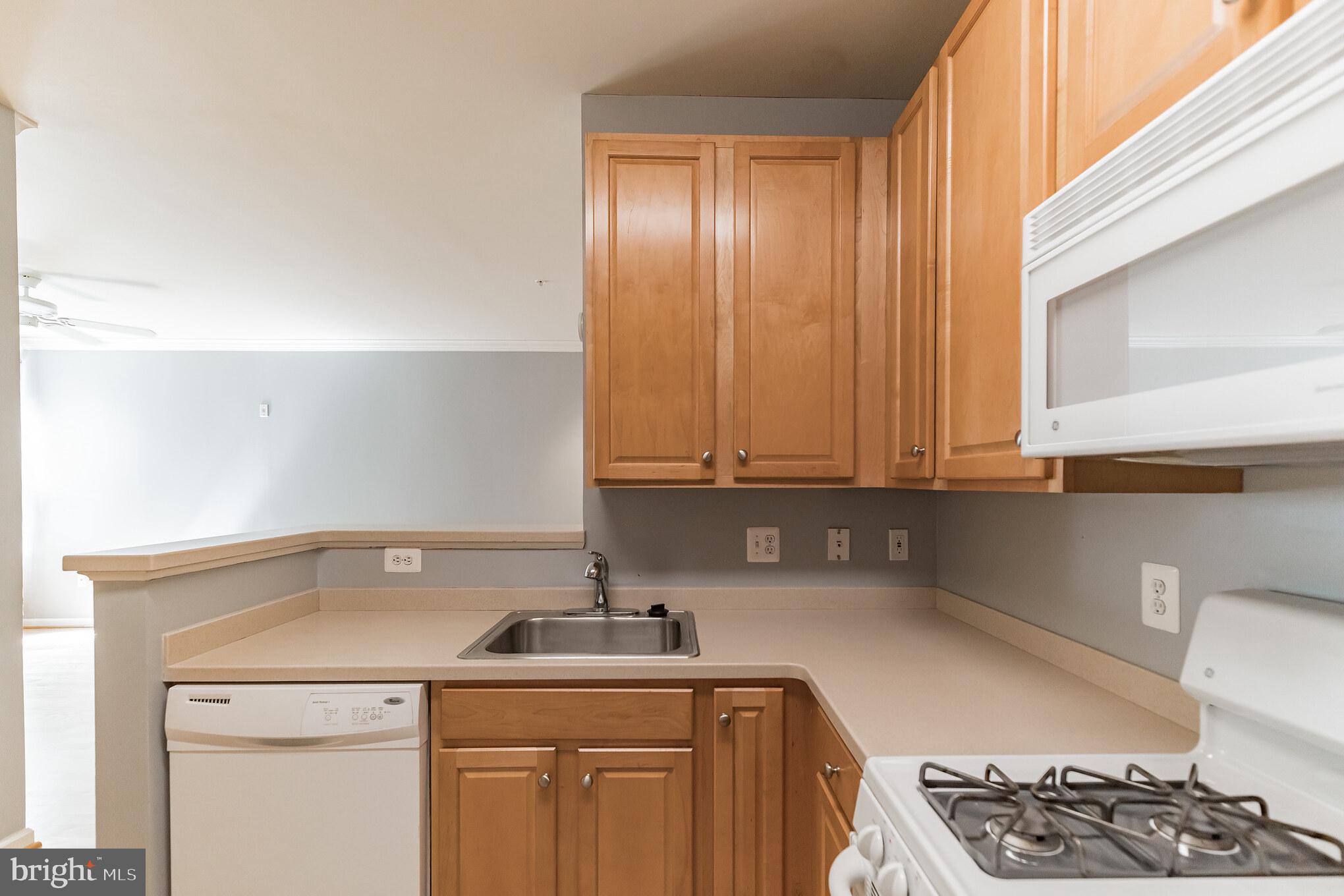 12001 Market Street, Unit 106 Reston, VA 20190 - Photo 10 of 26 a kitchen with a sink cabinets and stove top oven