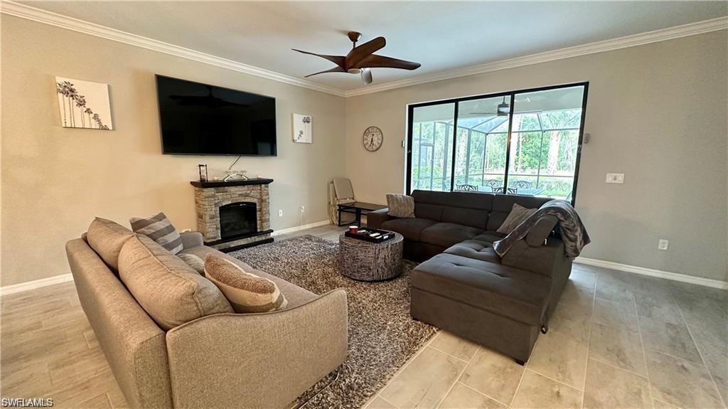 19347 Elston Way Estero, FL 33928 - Photo 5 of 26 Living area featuring baseboards, a fireplace, a ceiling fan, and crown molding