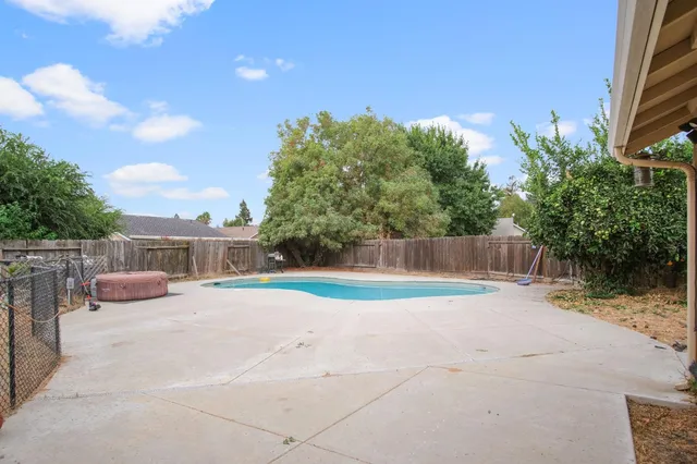 a view of backyard with swimming pool and seating space