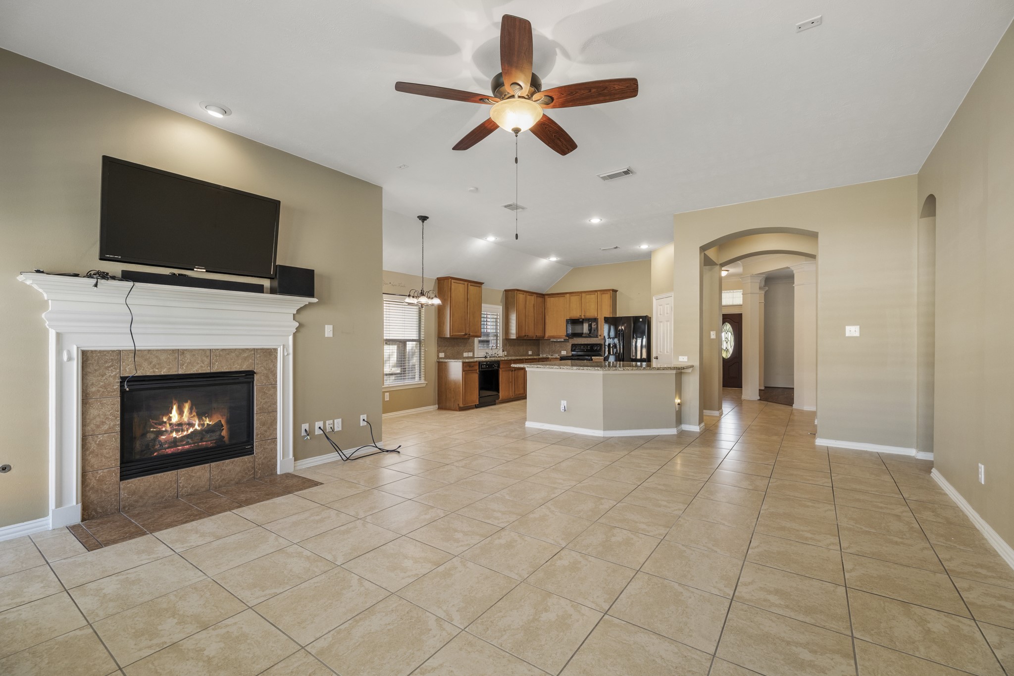 20014 Queens Oak Court Spring, TX 77379 - Photo 10 of 49 a view of a livingroom with a fireplace a fireplace a ceiling fan and a kitchen view