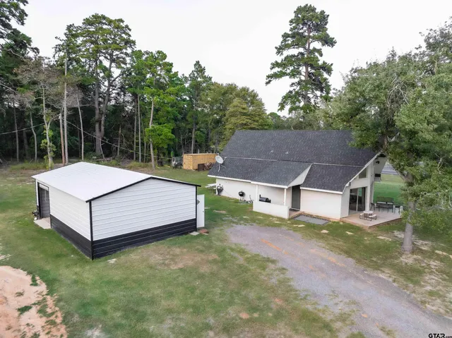 a view of a house with a yard and large trees