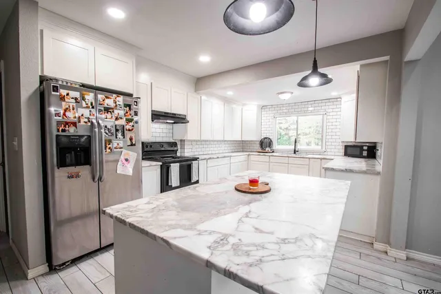 a kitchen with stainless steel appliances granite countertop a sink a refrigerator and a stove top oven