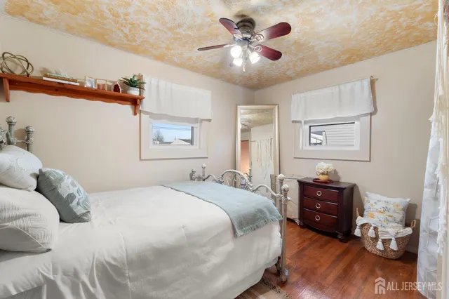 a bedroom with a bed dresser and wooden floor