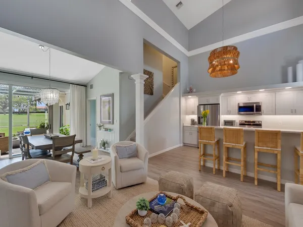 a living room with furniture a rug kitchen view and a large window