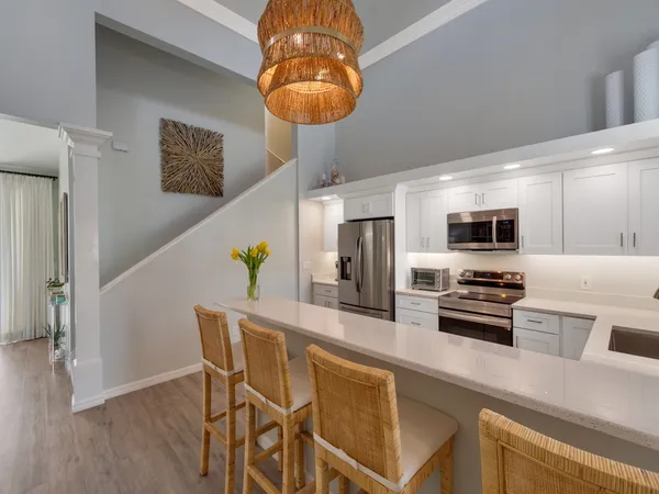 a kitchen with stainless steel appliances a dining table chairs refrigerator and microwave