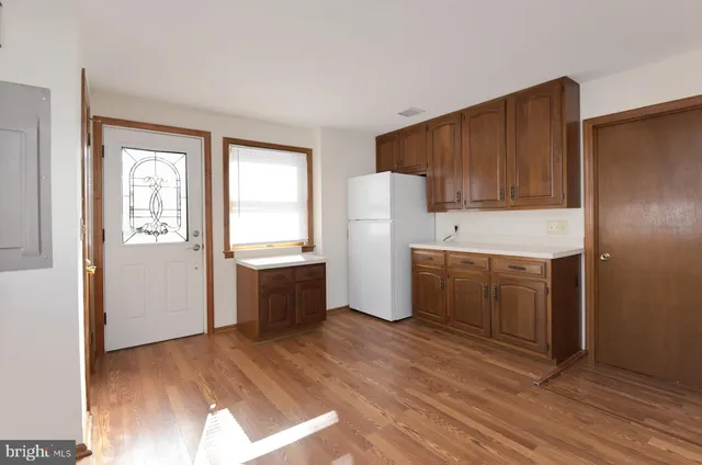 a kitchen with a refrigerator a stove top oven and wooden floors