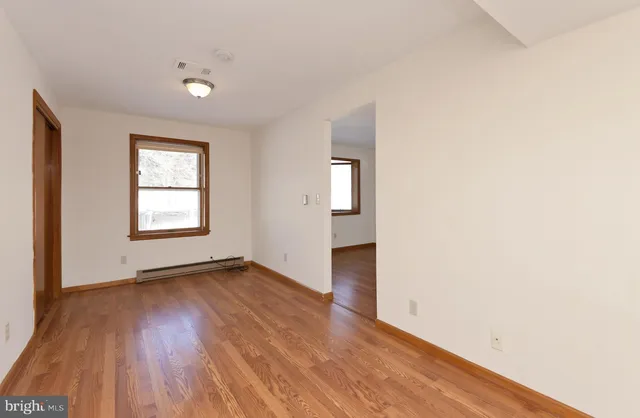 an empty room with wooden floor and windows