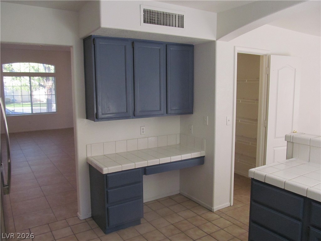 8701 Crescent Ridge Lane Las Vegas, NV 89134 - Photo 11 of 28 A functional kitchen workstation with tile counters and built-in cabinetry, perfect for culinary tasks.