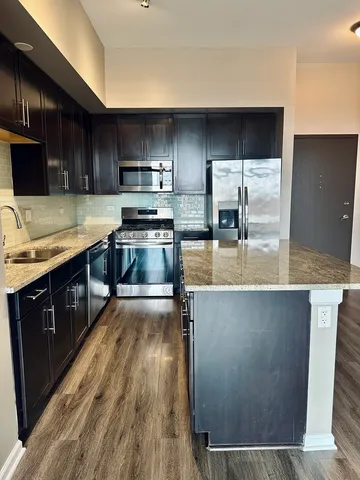 a kitchen with stainless steel appliances wooden cabinets a stove top oven a sink and dishwasher