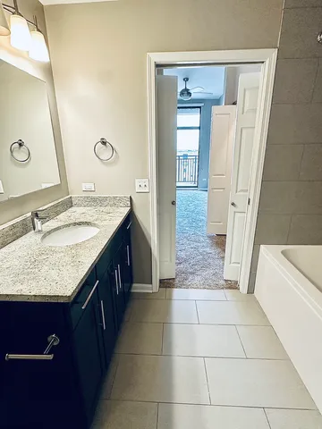 a bathroom with a granite countertop sink a mirror and a bathtub