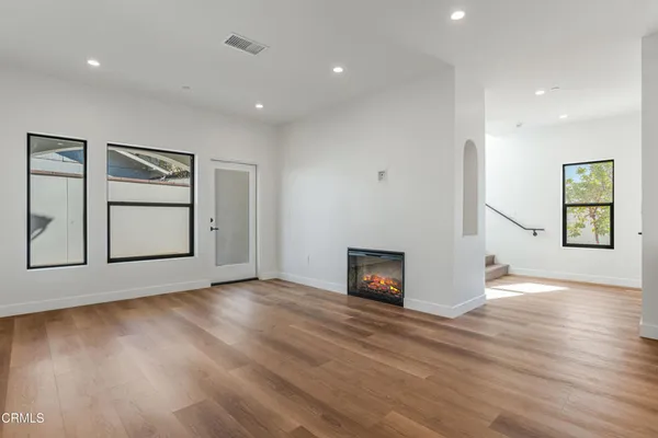a view of an empty room with window and wooden floor