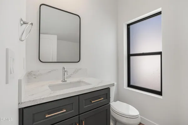 a bathroom with a toilet sink vanity and mirror