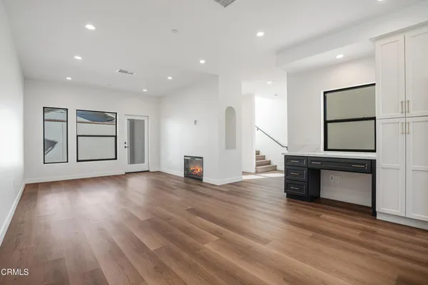 a view of an empty room with a window and wooden floor