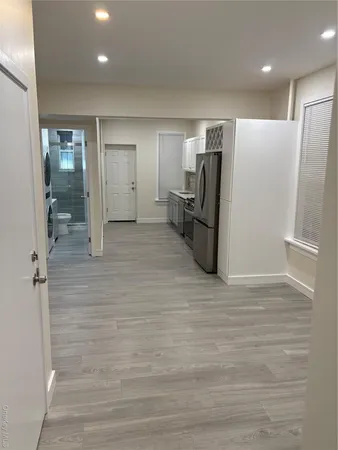 a view of a refrigerator in kitchen and an empty room