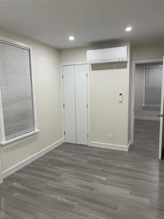 a view of an empty room with wooden floor and a mirror
