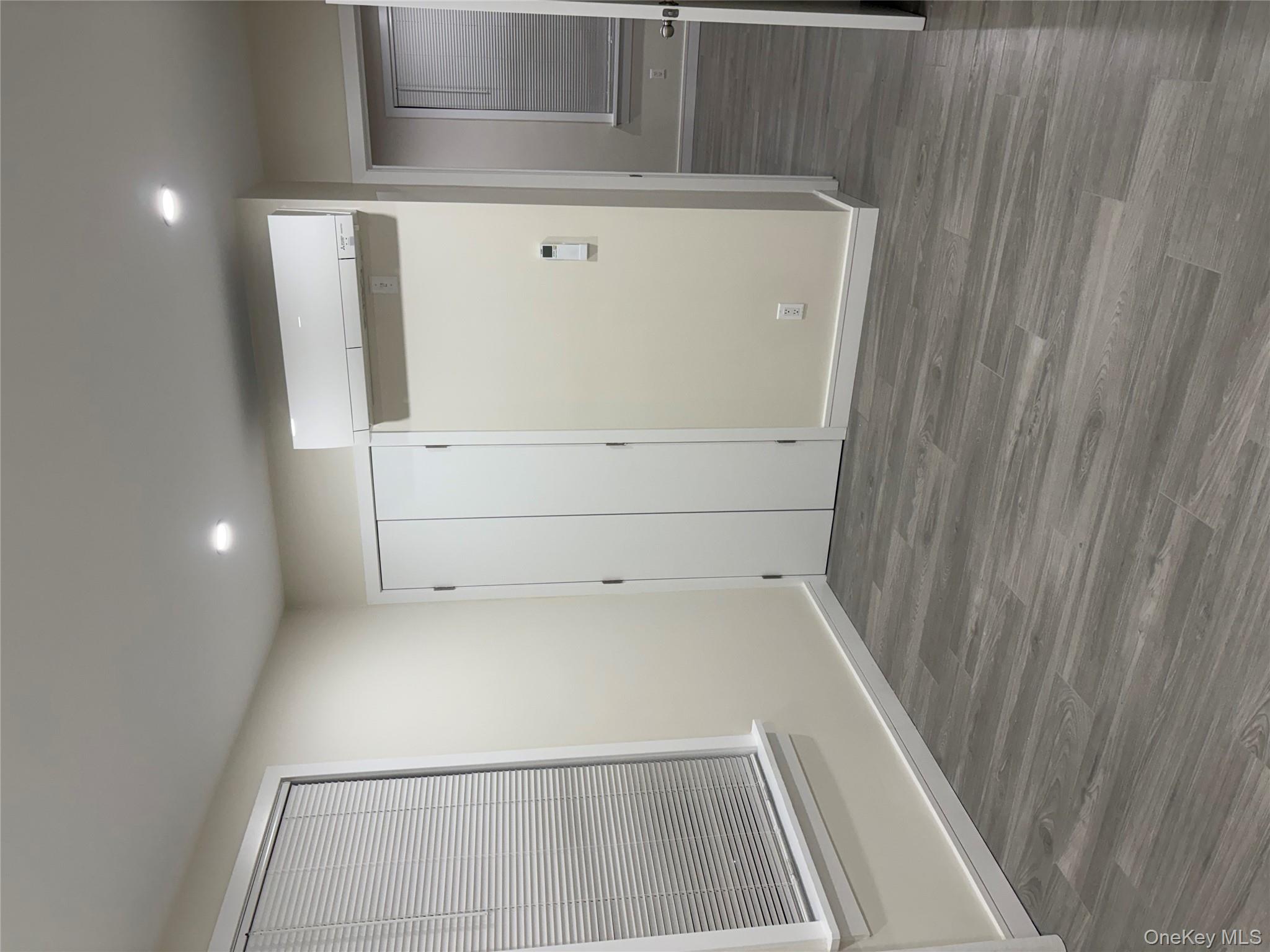 30-68 45th Street, Unit 1 Queens, NY 11103 - Photo 6 of 24 a view of an empty room with wooden floor and a mirror