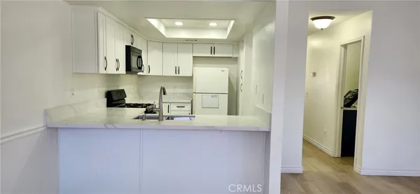 a kitchen with white cabinets and refrigerator