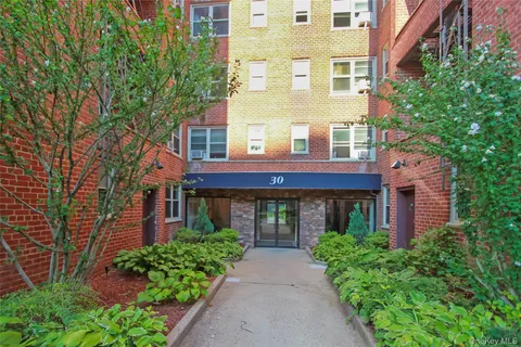 front view of a brick house with a large windows and a yard