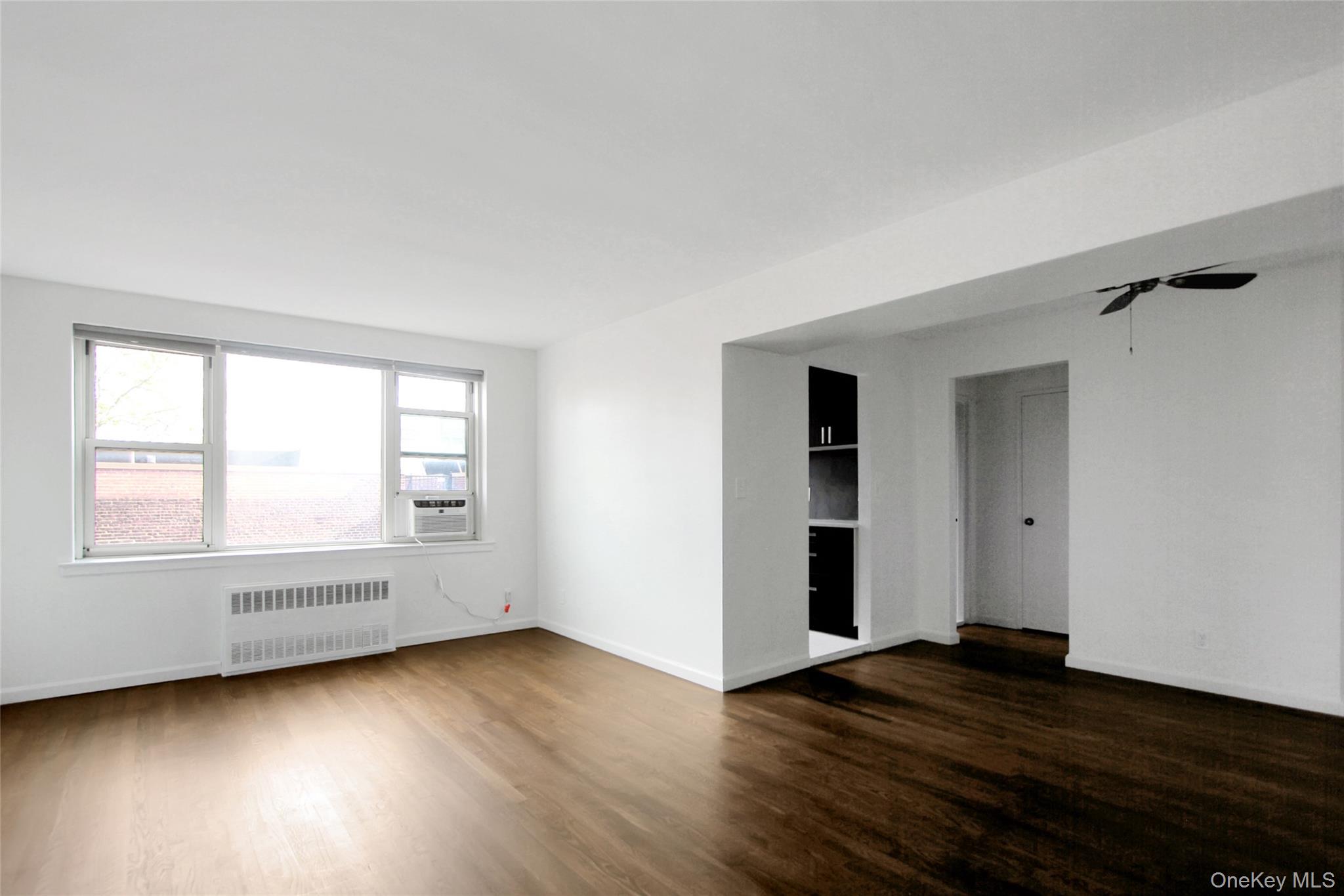 30 North Broadway, Unit 4C White Plains, NY 10601 - Photo 5 of 11 an empty room with wooden floor and windows