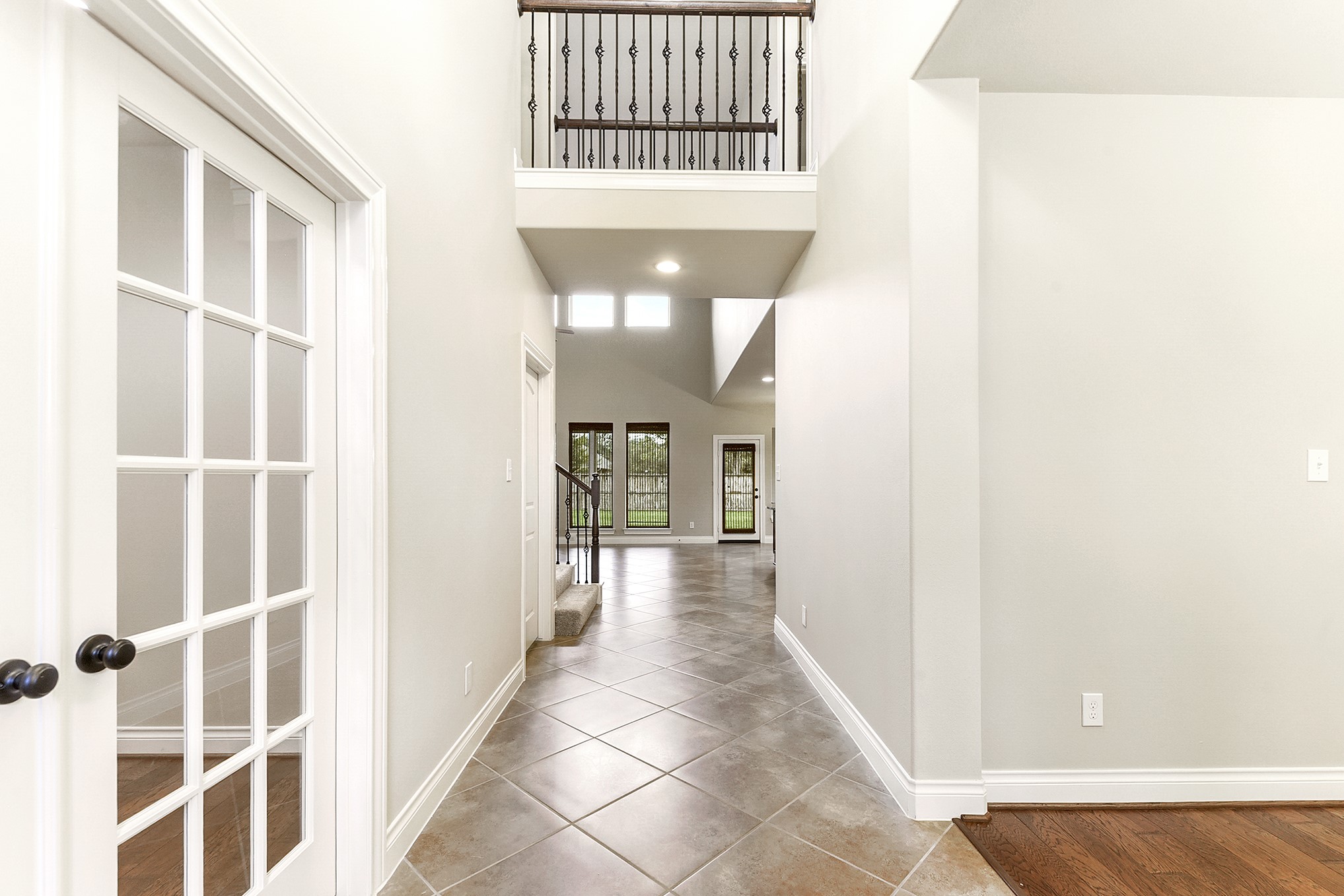 29023 Powder Ridge Drive Katy, TX 77494 - Photo 8 of 50 This view from the large, welcoming foyer captures the spacious entranceway and stunning sightlines into the expansive living room. Both the foyer and living room feature impressive two-story ceilings, creating an open and airy feel. To the right is the private home office, featuring elegant French doors.