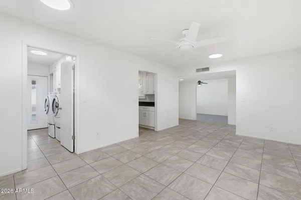 an empty room with kitchen and chandelier fan